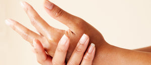 Close-up of two hands with one hand massaging the other on a beige background